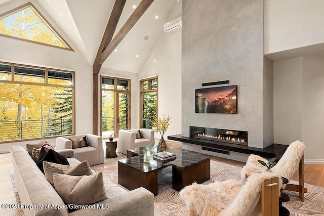 living room with a towering ceiling, a large fireplace, beamed ceiling, and light hardwood / wood-style flooring