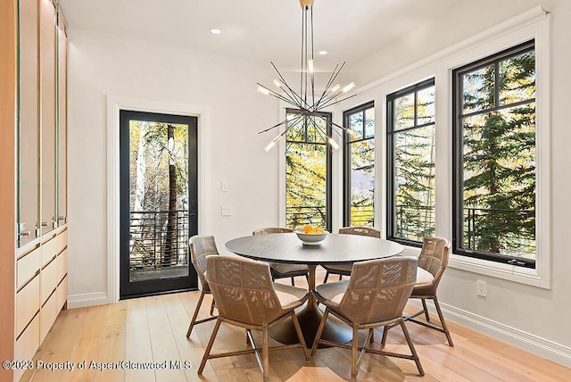 dining space with a notable chandelier, a healthy amount of sunlight, and light hardwood / wood-style flooring