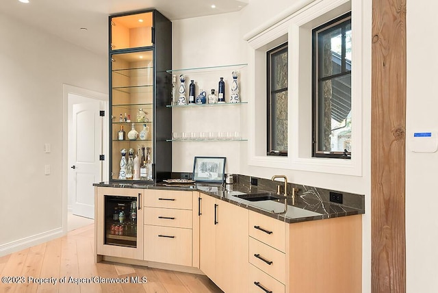 bar with a healthy amount of sunlight, sink, beverage cooler, and light hardwood / wood-style floors