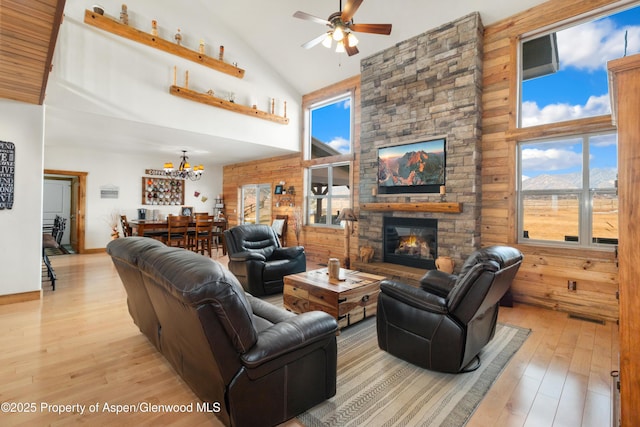 living room featuring a healthy amount of sunlight, a fireplace, high vaulted ceiling, and light wood-type flooring