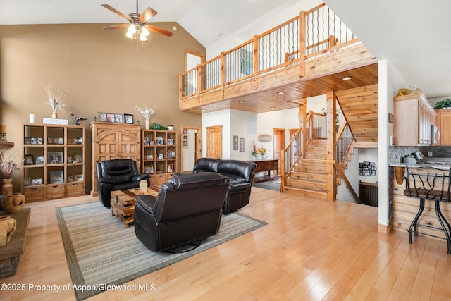 living room with ceiling fan, high vaulted ceiling, and light hardwood / wood-style floors