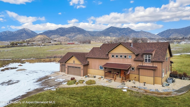 view of front of home with a garage, a mountain view, and a front yard