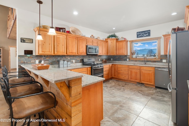 kitchen featuring a breakfast bar, hanging light fixtures, kitchen peninsula, stainless steel appliances, and light stone countertops