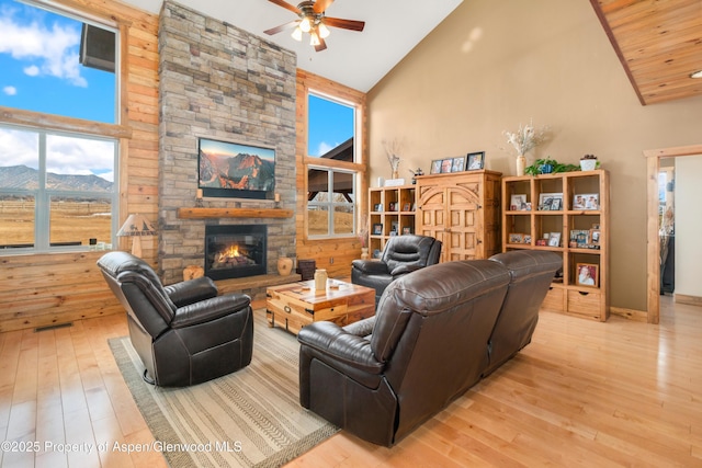 living room featuring a fireplace, high vaulted ceiling, ceiling fan, a mountain view, and light wood-type flooring