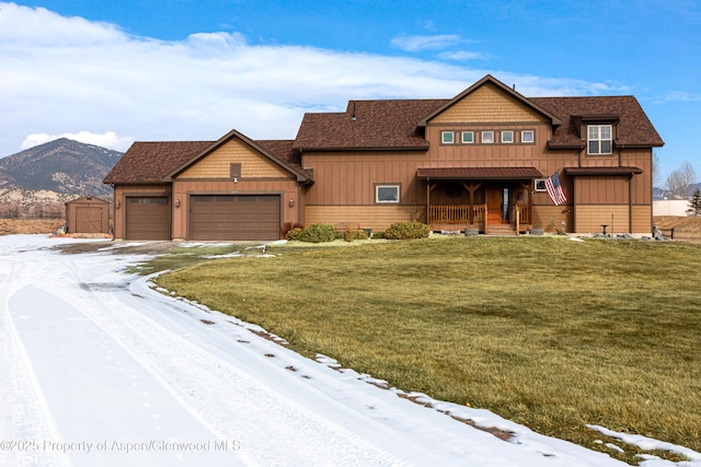 view of front of house featuring a porch, a garage, a mountain view, and a lawn