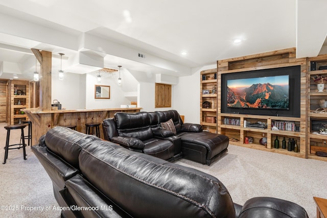 carpeted cinema room featuring bar area and built in shelves