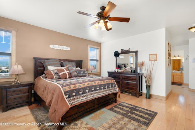 bedroom featuring light wood-type flooring, ceiling fan, and ensuite bathroom