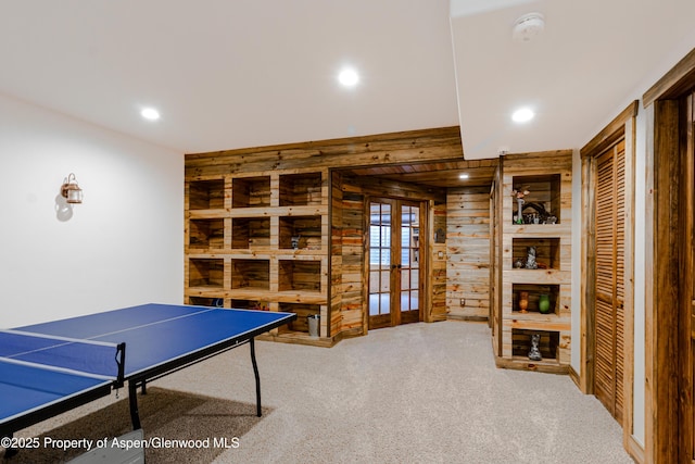 rec room with french doors, built in shelves, carpet, and wood walls