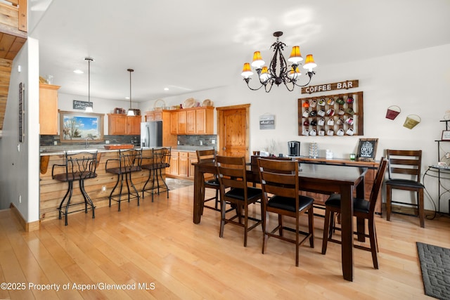 dining room with a notable chandelier, sink, and light wood-type flooring