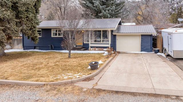 ranch-style home featuring a garage, a front yard, concrete driveway, and metal roof