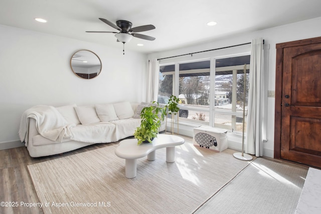 living room featuring baseboards, wood finished floors, a ceiling fan, and recessed lighting