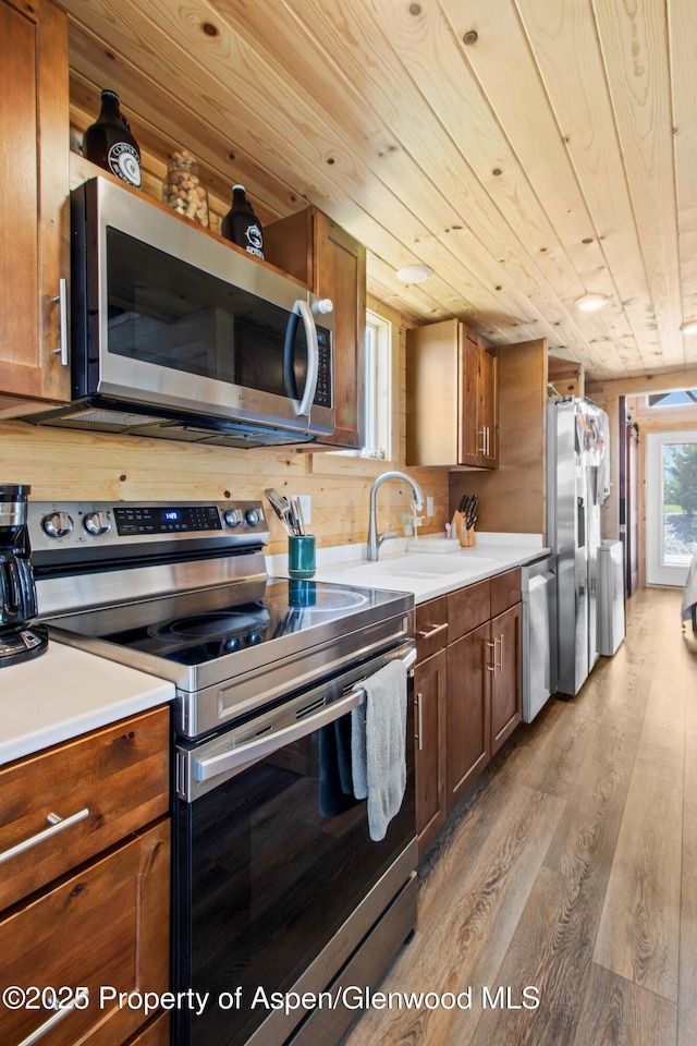 329 River Frontage Rd # 65, Silt, CO 81652 - kitchen featuring appliances with stainless steel finishes, light wood-style floors, wood ceiling, light countertops, and brown cabinetry