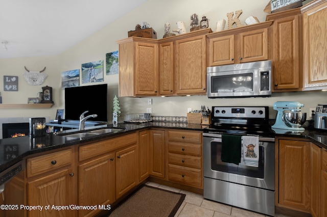 kitchen with stainless steel appliances, sink, dark stone countertops, and light tile patterned floors