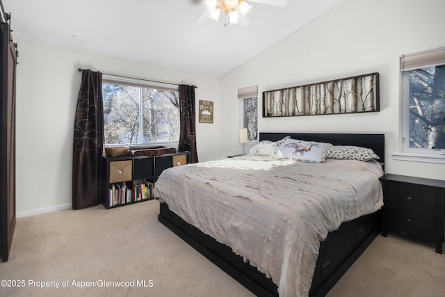 carpeted bedroom featuring vaulted ceiling, a barn door, and ceiling fan