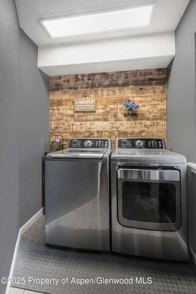 clothes washing area featuring independent washer and dryer and wood walls