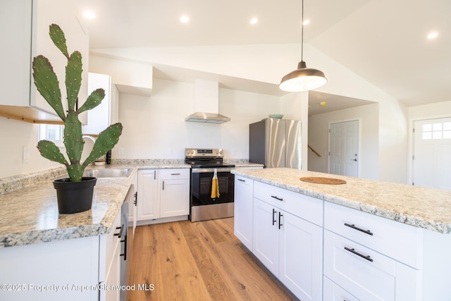 1720 Belgian Loop, Silt, CO 81652 - kitchen with stainless steel appliances, wall chimney range hood, vaulted ceiling, light wood finished floors, and white cabinetry