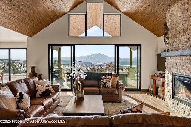 living room featuring wood ceiling, a healthy amount of sunlight, and a stone fireplace