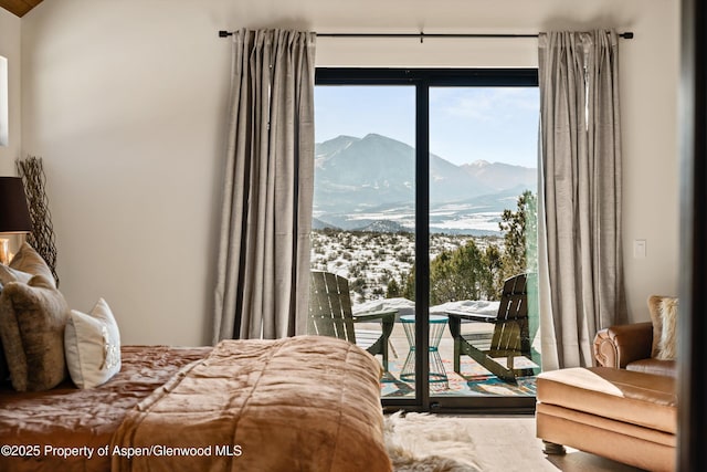 bedroom with multiple windows, a mountain view, and access to outside