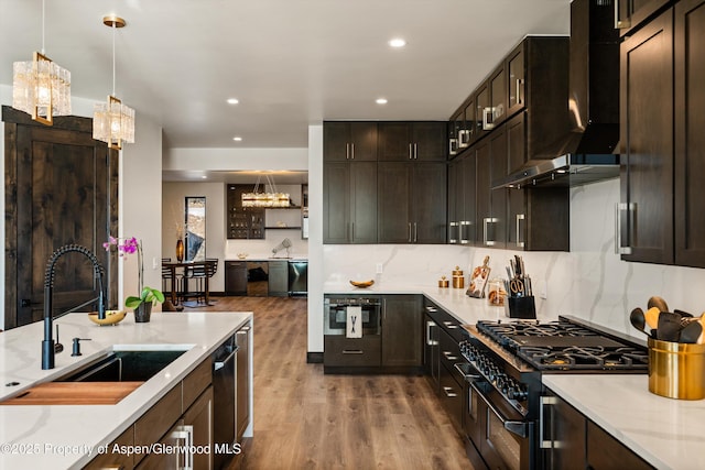 kitchen featuring sink, wall chimney range hood, double oven range, dark brown cabinetry, and a barn door