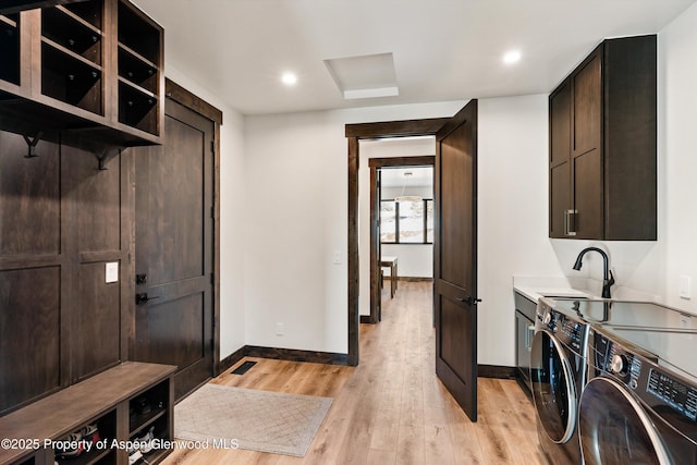 washroom with sink, washer and clothes dryer, light hardwood / wood-style floors, and cabinets