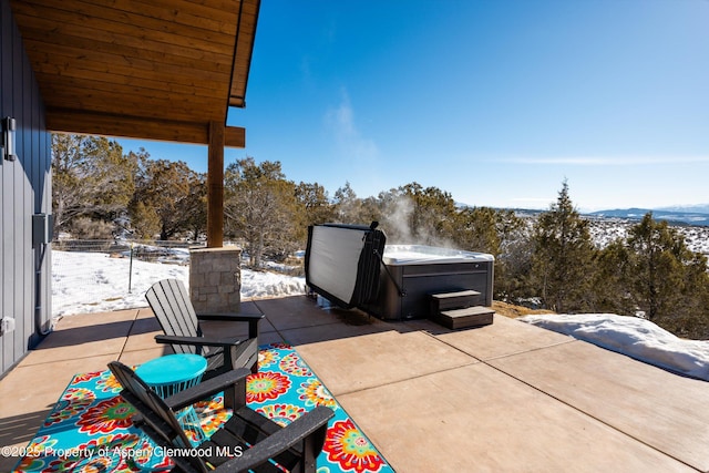 snow covered patio featuring a hot tub