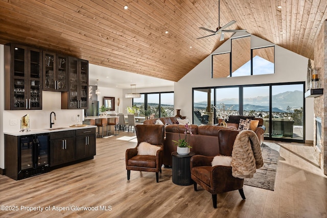 living room with sink, wine cooler, a mountain view, wooden ceiling, and light hardwood / wood-style flooring