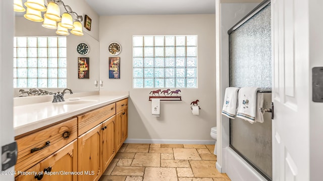 full bathroom featuring vanity, bath / shower combo with glass door, and toilet