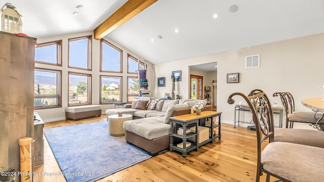 living room with beam ceiling, light wood-type flooring, and high vaulted ceiling