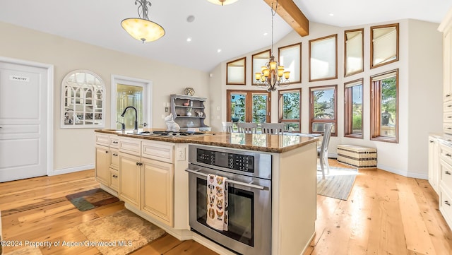 kitchen with appliances with stainless steel finishes, a center island with sink, an inviting chandelier, light hardwood / wood-style flooring, and hanging light fixtures