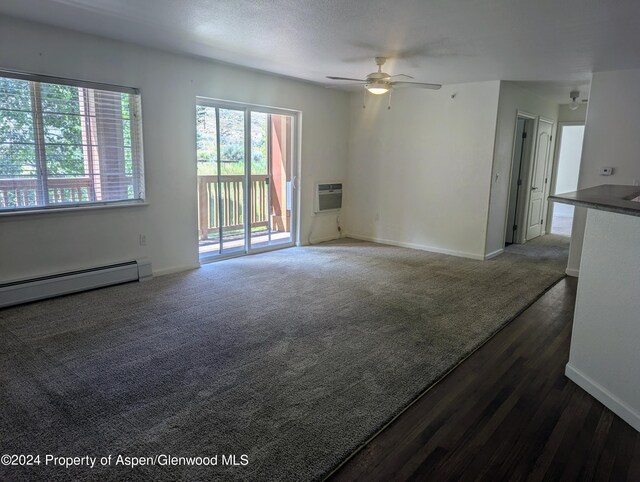 unfurnished living room featuring dark colored carpet, ceiling fan, a wall unit AC, and a baseboard radiator