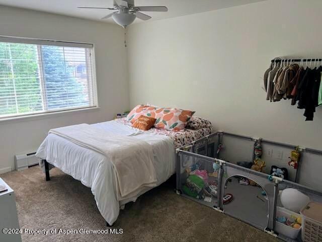 carpeted bedroom with ceiling fan and baseboard heating