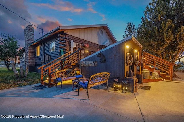 550 County Road 22, Craig, CO 81625 - back of property at dusk with a patio, a chimney, log exterior, and stairway