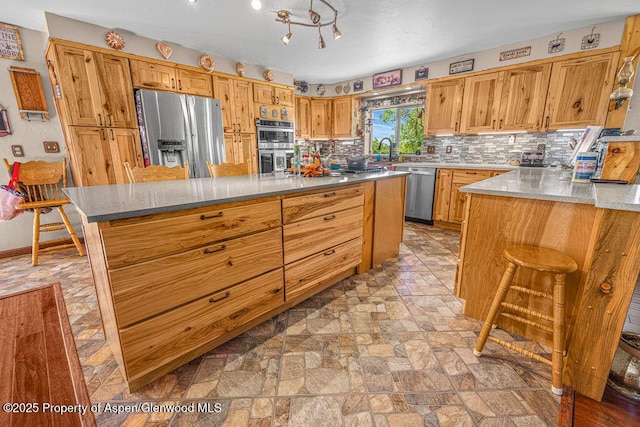 550 County Road 22, Craig, CO 81625 - kitchen featuring stainless steel appliances, decorative backsplash, light stone finish floors, a center island, and light stone counters
