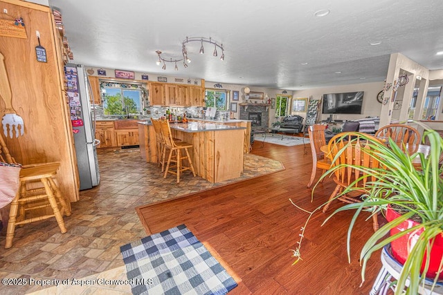 550 County Road 22, Craig, CO 81625 - kitchen with freestanding refrigerator, brown cabinets, a center island, a breakfast bar area, and recessed lighting
