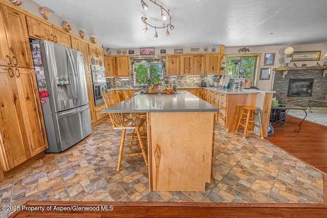 550 County Road 22, Craig, CO 81625 - kitchen with appliances with stainless steel finishes, a kitchen breakfast bar, backsplash, a kitchen island, and light stone finish floors