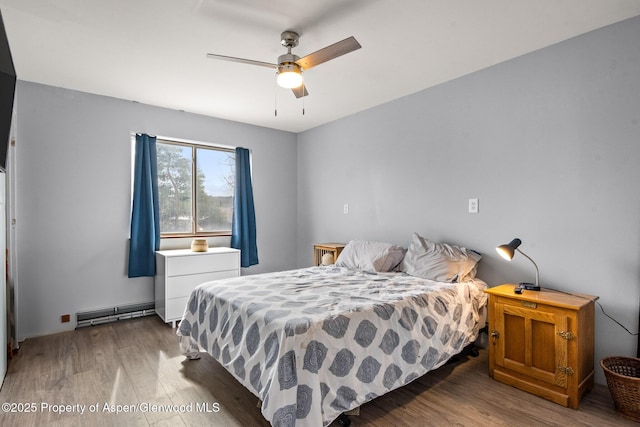 bedroom with wood finished floors, a ceiling fan, and a baseboard radiator