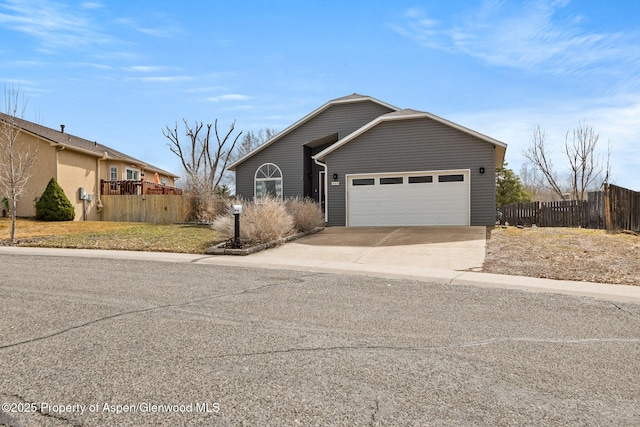 view of front of house with an attached garage, driveway, and fence