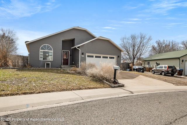 view of front of house with an attached garage, concrete driveway, a front yard, and fence