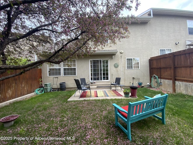 758 Pine Ct, New Castle, CO 81647 - back of property with a fenced backyard, a patio area, stucco siding, and a yard