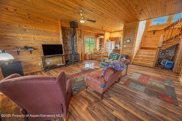1349 Eagle Loop, Craig, CO 81625 - living room featuring a wood stove, stairway, ceiling fan, wood finished floors, and wood walls