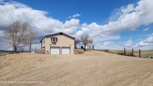 3294 County Road 103, Craig, CO 81625 - exterior space featuring an attached garage, stucco siding, driveway, and fence