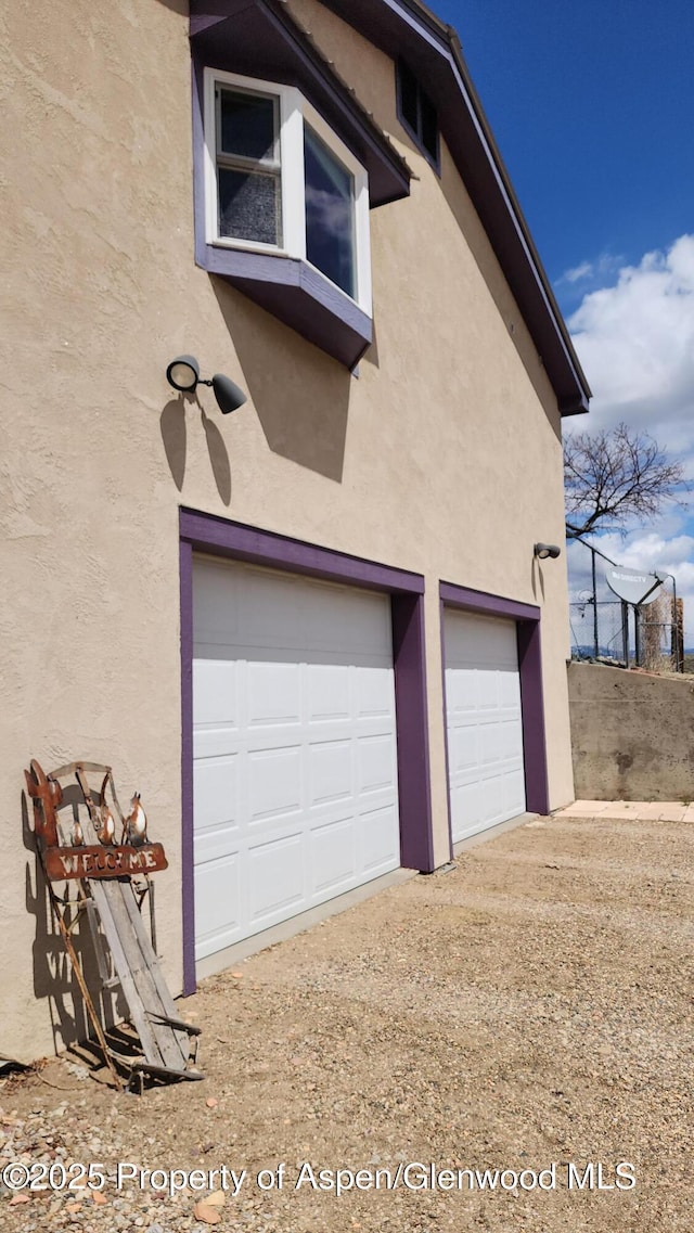 3294 County Road 103, Craig, CO 81625 - view of home's exterior featuring an attached garage, dirt driveway, stucco siding, and fence