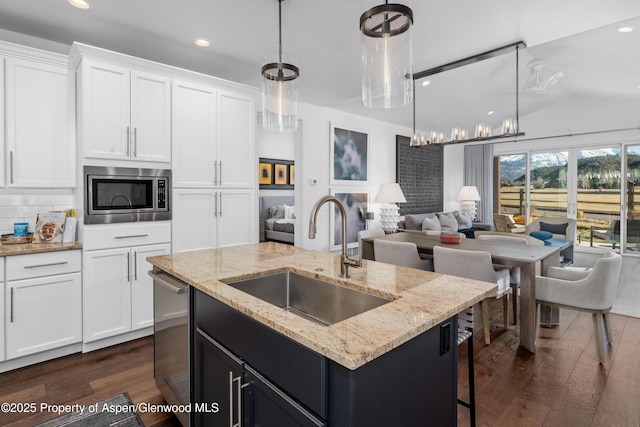 kitchen featuring dark wood-style floors, a sink, appliances with stainless steel finishes, white cabinetry, and open floor plan