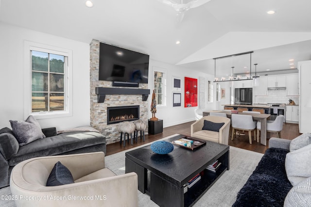 living area with a fireplace, lofted ceiling, recessed lighting, and wood finished floors