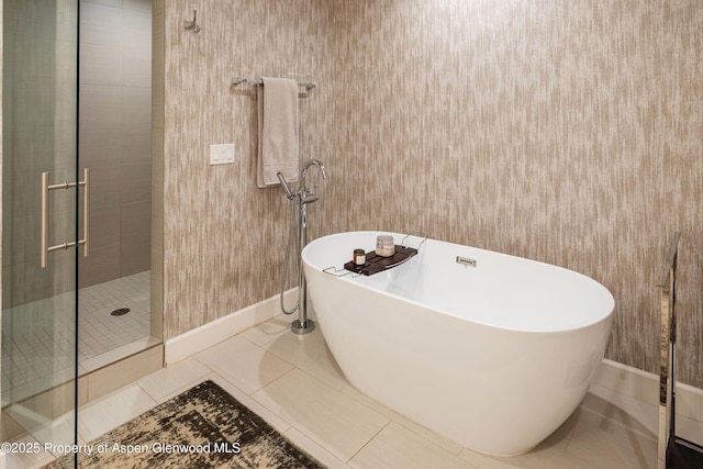 full bathroom featuring tile patterned floors, a shower stall, baseboards, and a freestanding tub