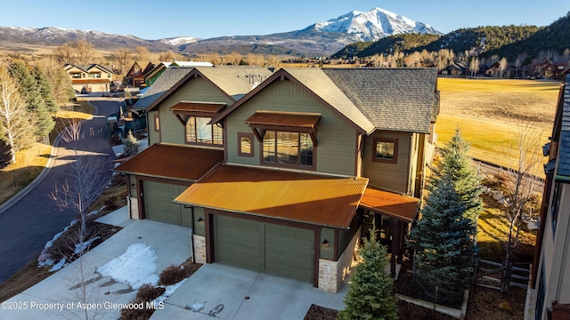 chalet / cabin with a mountain view, driveway, a garage, and stone siding