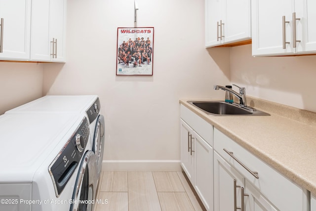 clothes washing area featuring a sink, baseboards, cabinet space, and washing machine and dryer