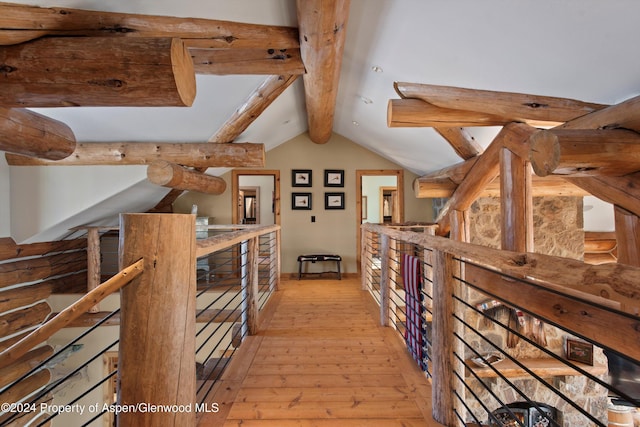 hallway featuring light wood-type flooring and vaulted ceiling with beams