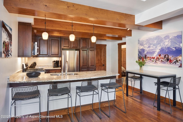 kitchen with appliances with stainless steel finishes, sink, a breakfast bar area, kitchen peninsula, and light stone countertops