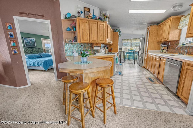 1097 Kowach Dr, Craig, CO 81625 - kitchen featuring a sink, stainless steel appliances, light countertops, a peninsula, and decorative backsplash